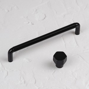 May include: Black cabinet hardware set with a long, rectangular handle and a hexagonal knob.