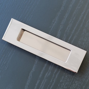 Peut inclure: Une poignée de tiroir rectangulaire en chrome poli avec une poignée encastrée.