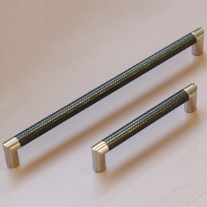 Può includere: Due maniglie per armadietti nere con finitura testurizzata e tappi terminali argentati. La maniglia più grande è lunga 30 cm e la più piccola 15 cm.