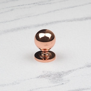 Peut inclure: Un bouton de porte en cuivre poli avec une forme de boule ronde et une base circulaire.