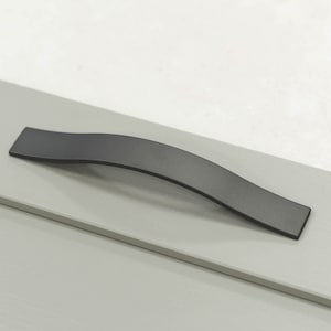 May include: A matte black cabinet pull with a wavy design. The handle is rectangular and mounted on a light gray surface. The pull is approximately 8 inches long.