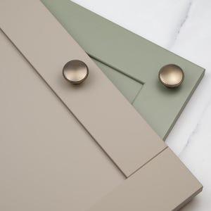 Könnte beinhalten: Zwei Schranktüren in unterschiedlichen Farben, eine in hellem Beige und die andere in hellem Grün. Beide Türen haben einen runden, gebürsteten Nickel-Schrankknauf.