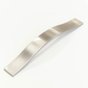 Puede incluir: Un tirador de armario de níquel cepillado con un diseño curvo.