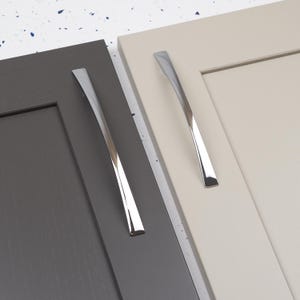 Pode incluir: Duas portas de armário com acabamentos diferentes, uma cinza e outra bege, cada uma com uma puxador de armário cromado.