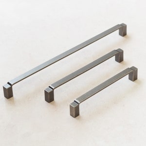 Op de afbeelding: Drie zilveren metalen kastgrepen in verschillende maten. De grepen zijn rechthoekig met afgeronde hoeken.