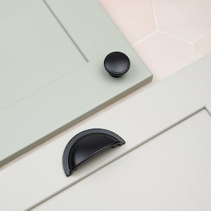 May include: Two black cabinet hardware pulls, one round knob and one half-circle cup pull.