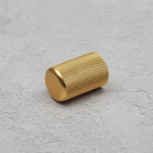 Peut inclure: Un bouton de porte en métal doré avec un motif texturé en diamant.