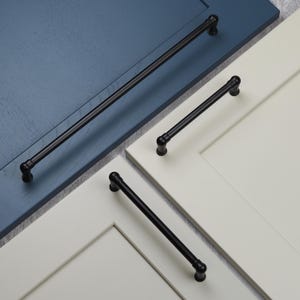 May include: Three black metal cabinet pulls with rounded ends. The pulls are shown mounted on white and blue cabinet doors.