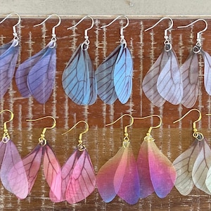 May include: A set of 10 pairs of delicate butterfly wing earrings. The earrings are made of translucent fabric and come in a variety of colors, including blue, purple, pink, and green.