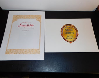 May include: Two white pieces of paper with a gold frame and the text "Snow White and the Seven Dwarfs" in red and gold lettering. The text is in a mirror-like shape.