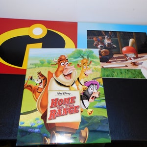 Könnte beinhalten: Ein farbenfrohes Plakat für den Disney-Film "Home on the Range" mit einer Kuh, einem Pferd und einem Hahn. Das Plakat ist vor einem grünen Feld mit blauen Blumen platziert. Der Titel des Films ist in roten und weißen Buchstaben.
