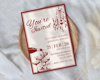 May include: A rectangular invitation with a red border and text that reads "You're Invited" in a cursive font. The invitation includes details for a cocktail party, with a chandelier illustration and champagne glasses.