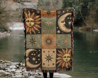 May include: A tapestry throw blanket with a patchwork design featuring suns, moons, and stars in shades of gold, brown, and blue. The blanket has fringe along the edges.