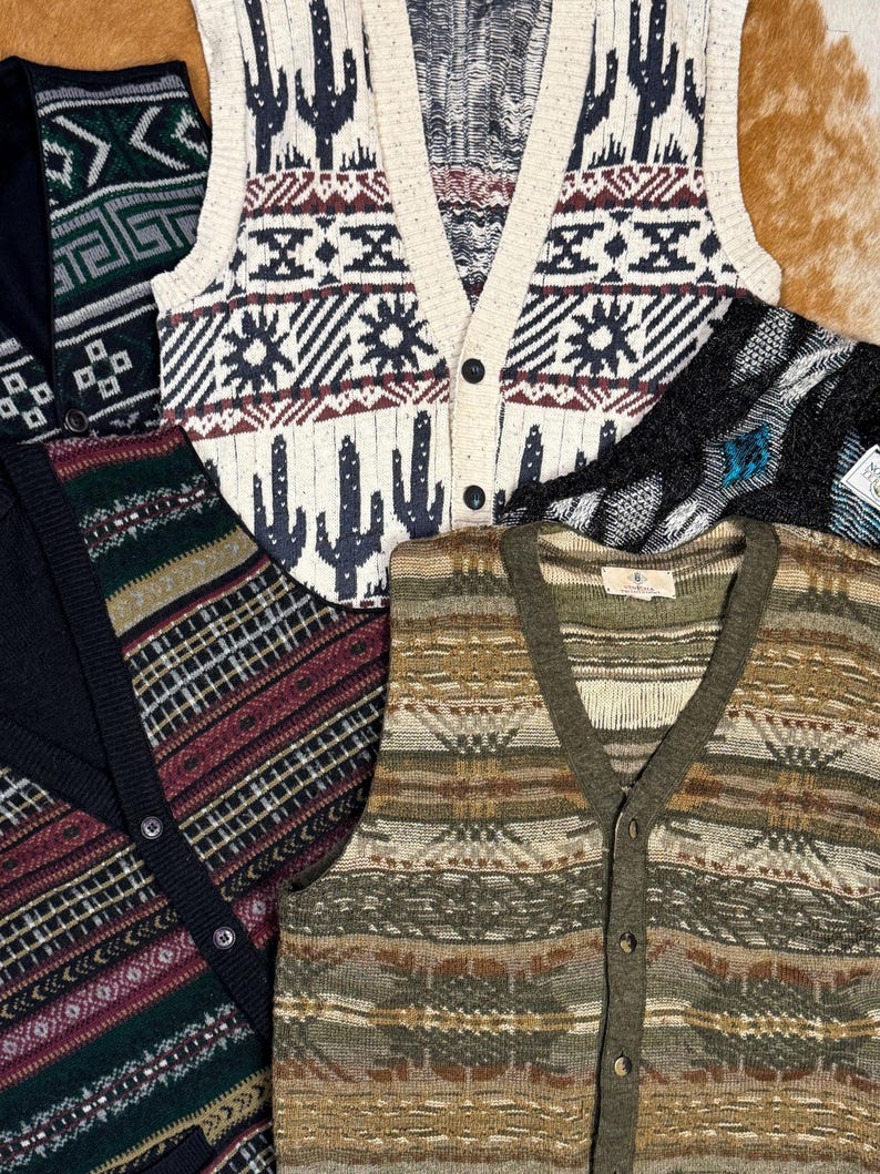 May include: Five different patterned knitted vests with button closures. The vests are in various colors, including black, white, brown, green, and red. The patterns are geometric and abstract.
