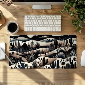 May include: A black and white illustrated mousepad featuring a desert landscape with cacti and other desert plants. The background is a dark blue with stars.