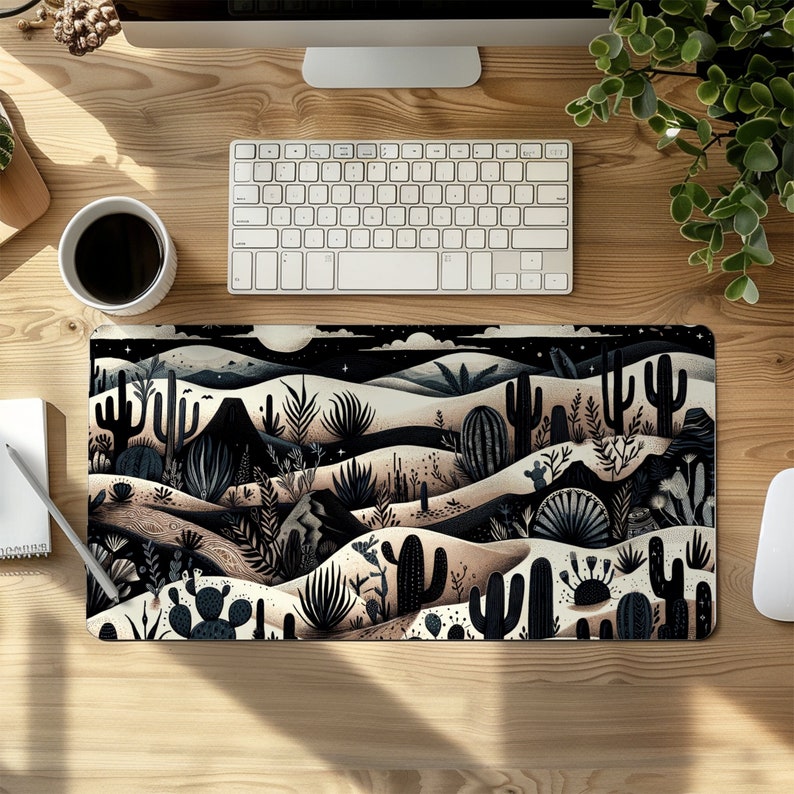 May include: A black and white illustrated mousepad featuring a desert landscape with cacti and other desert plants. The background is a dark blue with stars.