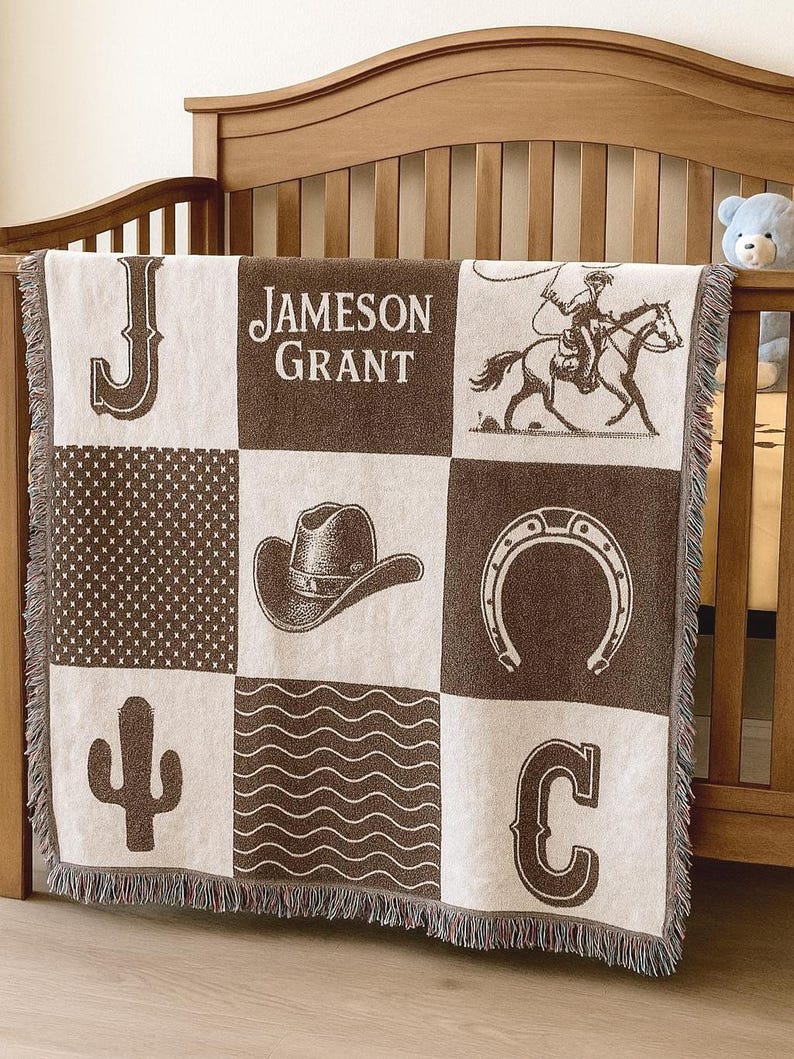 May include: A woven throw blanket featuring a grid of nine squares in brown and cream. The design includes the name Jameson Grant, the letters J and C, a cowboy on a horse, a cowboy hat, a horseshoe, a cactus, and geometric patterns.