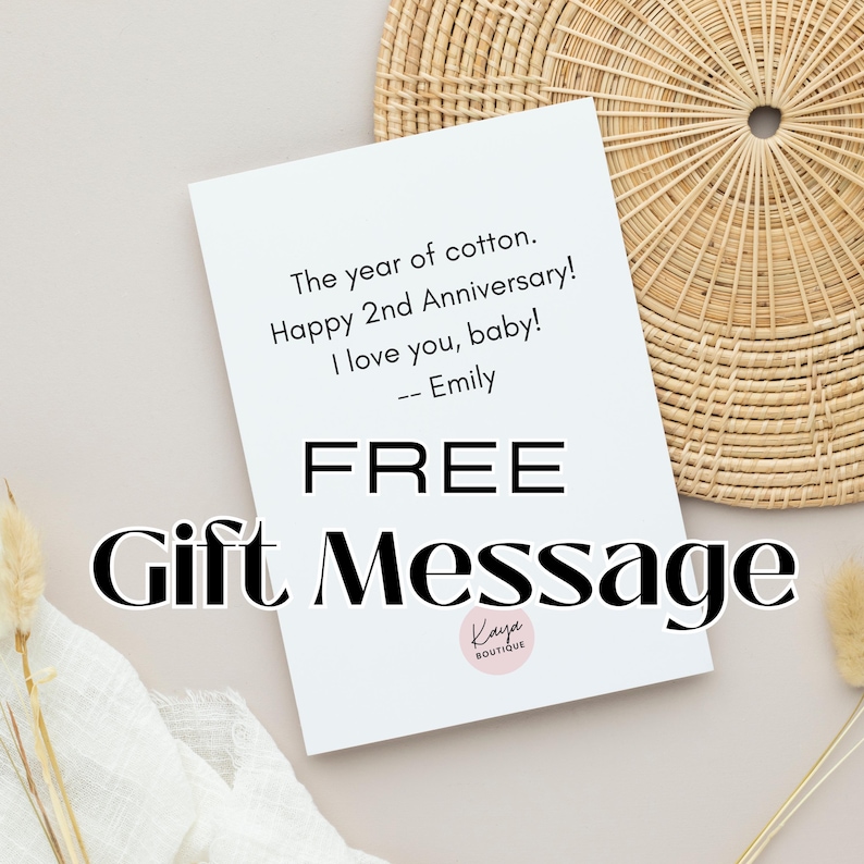 May include: A white card with the text "The year of cotton. Happy 2nd Anniversary! I love you, baby! -- Emily" and "FREE Gift Message". The card is placed on a light beige surface with a woven basket and dried flowers in the background.