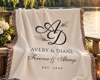 May include: A cream-colored woven throw blanket with fringed edges featuring a black printed monogram of the letters A and D, the names Avery & Diane, the phrase Forever & Always, and the text EST. 2023 in a centered layout.