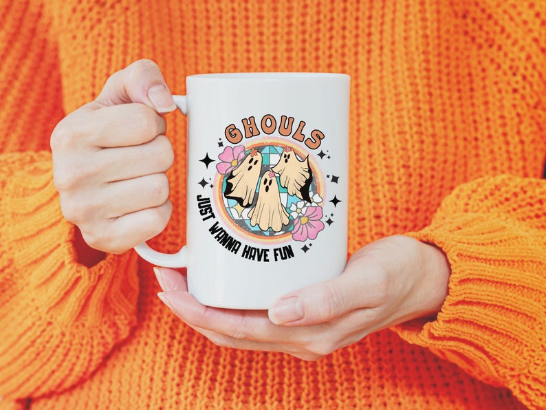 May include: White ceramic mug with a colorful graphic of three ghosts and the text "Ghouls Just Wanna Have Fun".