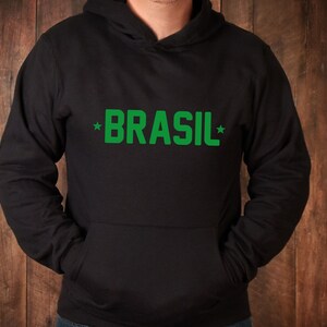 Puede incluir: Una sudadera con capucha negra con un gr&aacute;fico verde *BRASIL* en la parte delantera.