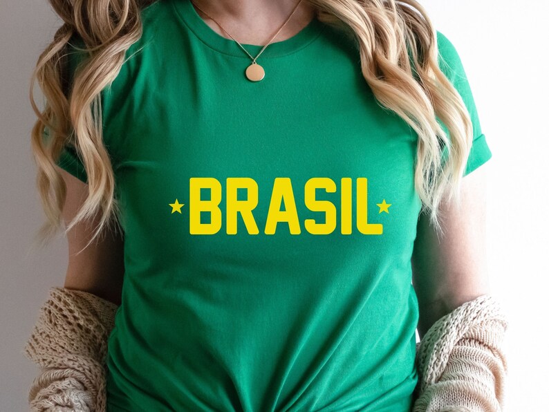 Puede incluir: Camiseta verde con la palabra "BRASIL" en letras amarillas y una estrella amarilla a cada lado de la palabra.