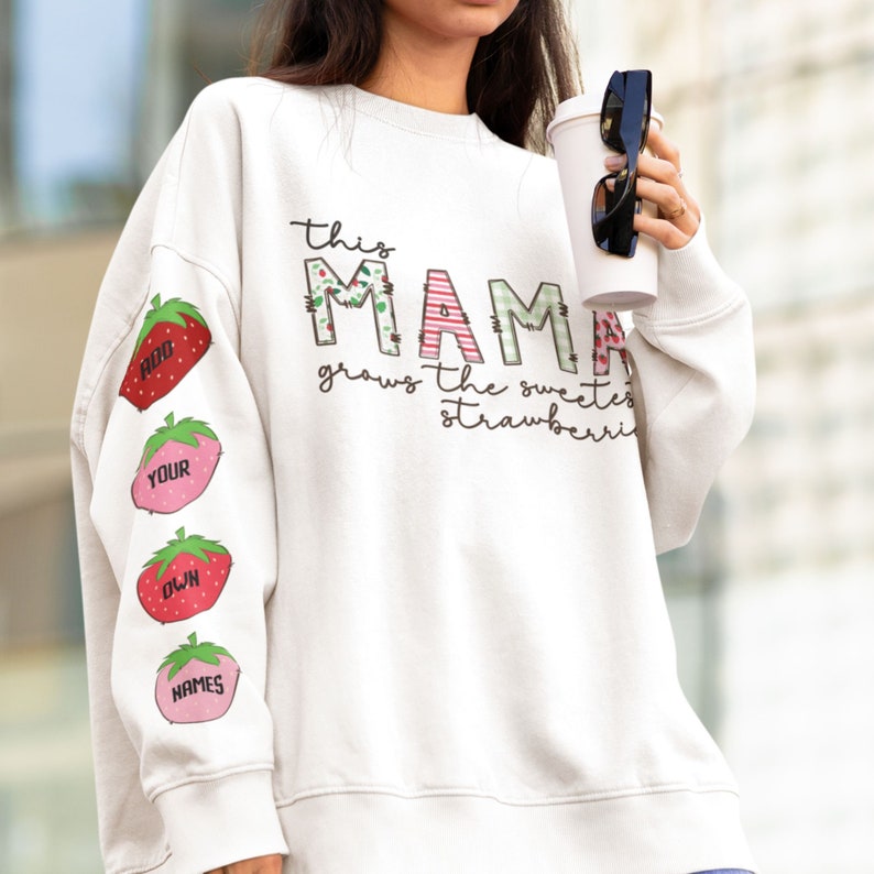 May include: White sweatshirt with the text "This Mama grows the sweetest strawberries" and four red strawberries with names on them on the sleeves.