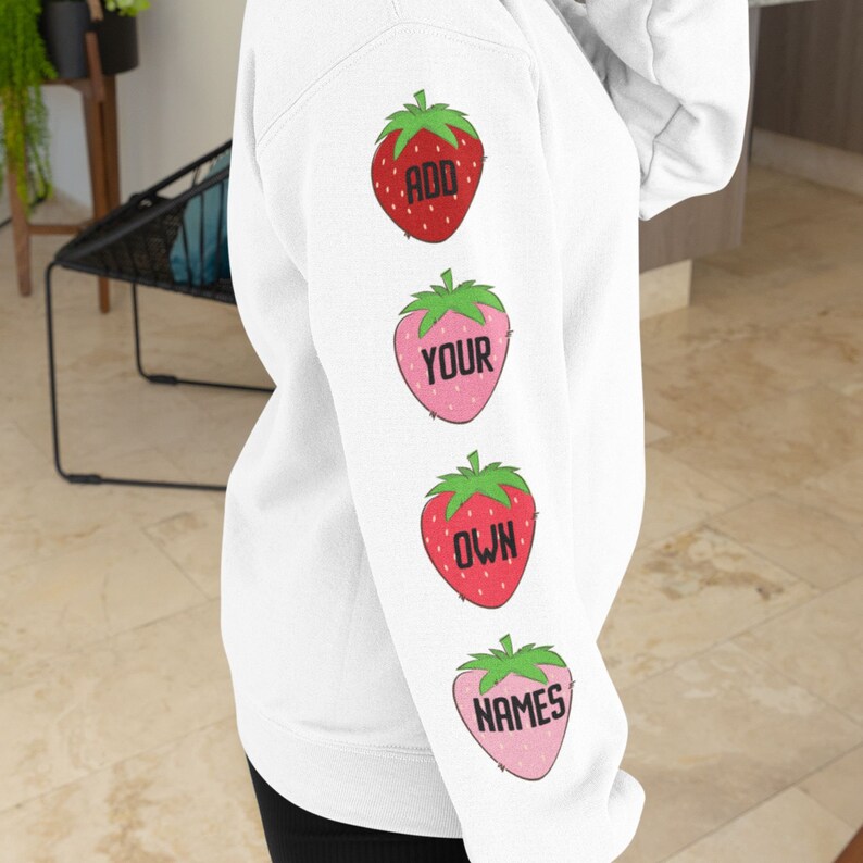 May include: White hoodie with a red and pink strawberry design on the sleeve. The strawberries have the words "ADD YOUR OWN NAMES" written on them.