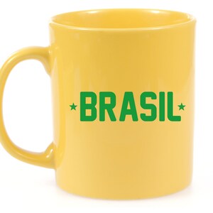 Puede incluir: Una taza de cer&aacute;mica amarilla con una inscripci&oacute;n verde que dice "*BRASIL*"