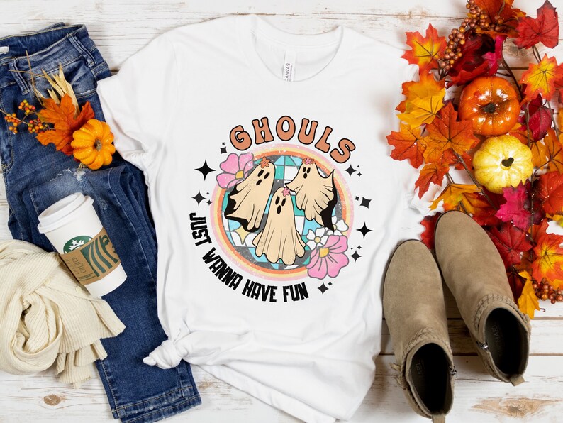May include: White t-shirt with a retro-style graphic of three ghosts in a circle with the text "Ghouls Just Wanna Have Fun".