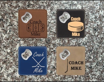 May include: Four different brown, black, blue, and tan leatherette bottle openers with a hockey theme. Each opener has a different design with the word "Coach" and the name "Mike" engraved on it.
