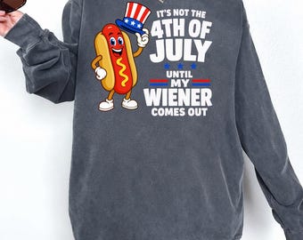 May include: A charcoal grey long-sleeve sweatshirt featuring a graphic of a cartoon hot dog wearing a patriotic top hat. The text reads: IT'S NOT THE 4TH OF JULY UNTIL MY WIENER COMES OUT. The design includes red, white, and blue accents.