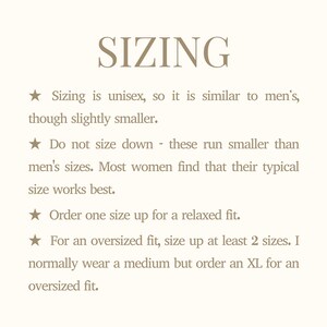 Może przedstawiać: Kremowa grafika z napisem "SIZING" w kroju pisma szeryfowego. Tekst poniżej zawiera porady dotyczące rozmiar&oacute;w, wskazując, że jest unisex, podobny do męskiego, ale nieco mniejszy. Zaleca się wyb&oacute;r rozmiaru większego dla luźnego lub oversize'owego kroju.