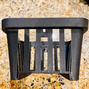 May include: A black plastic plant pot with a grid pattern. The pot is designed to be hung on a wall.