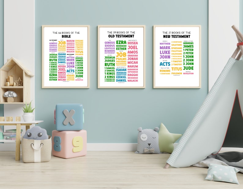 May include: Three framed prints with colorful text listing the books of the Bible. The prints are hung on a light blue wall in a child's room. The room has a wooden shelf, a toy tent, and a few toys.