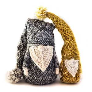 Puede incluir: Dos gnomos de punto, uno gris y otro amarillo, con pompones blancos en sus gorros y barbas de punto blanco.