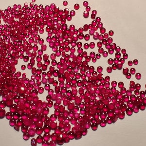 以下が含まれることがあります： 白い表面に散らばった、小さく丸い赤い宝石の大きなグループ。宝石はすべてほぼ同じサイズで、光沢のある研磨仕上げになっています。
