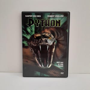 May include: A DVD case for the movie Python, featuring a large snake with its mouth open, showing sharp fangs. The text reads Python, Casper Van Dien, Robert Englund, and Sixty Feet of Pure Terror. The background is a dark green and black radial burst.