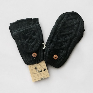 May include: A pair of black alpaca fingerless gloves with a cable knit pattern and wooden buttons. The gloves are on a white surface with a brown tag that says "Alpaca Knits" and has a picture of an alpaca.