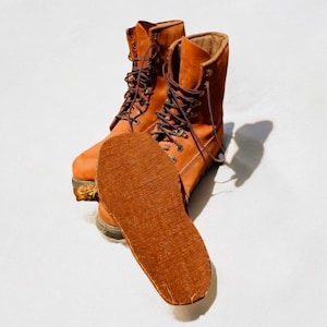 May include: A pair of brown leather boots with laces. The boots are worn and have a brown felt insole.