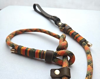 May include: A dog leash and matching collar set. The leash features a dark brown leather handle and accents, with a colorful rope design in orange, green, and yellow. The collar has a similar rope design and leather accents.