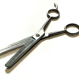 May include: Silver hairdressing shears with a serrated blade on one side. The shears have a classic design with two round handles.