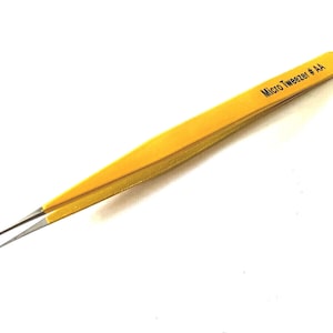 以下が含まれることがあります： 黄色いマイクロピンセット。先端が尖っており、黒い文字で「Micro Tweezer # AA」と書かれています。精密作業用に設計されており、白い背景に配置されています。