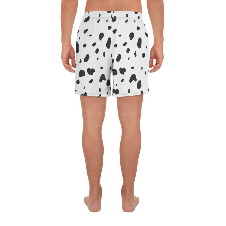 May include: White athletic shorts with a black dalmatian spot pattern. The shorts have an elastic waistband and are made of a lightweight material. The shorts are knee-length.