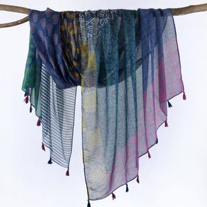 May include: A blue and green patterned scarf with tassels. The scarf is made of a lightweight fabric and features a variety of different patterns.