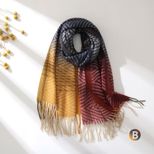 May include: A colorful scarf with a geometric pattern in shades of yellow, red, and blue. The scarf has a fringe border and is folded in a loop.