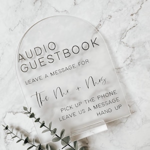 May include: Clear acrylic sign with black text that reads "AUDIO GUESTBOOK LEAVE A MESSAGE FOR The Mr. + Mrs. PICK UP THE PHONE LEAVE US A MESSAGE HANG UP"