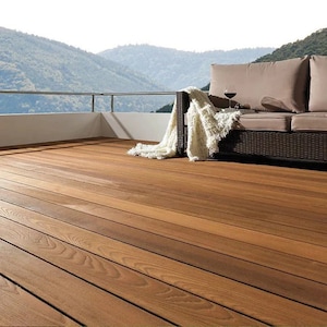 May include: A wooden deck with a brown wicker sofa and a white throw blanket. The deck overlooks a mountain range.