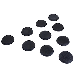 Könnte beinhalten: Zehn kleine, schwarze, kreisförmige Objekte mit leicht strukturierter Oberfläche auf weißem Hintergrund. Die Objekte sind gleichmäßig verteilt, eines ist links isoliert.