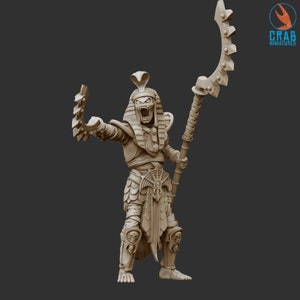 Könnte beinhalten: Beige Miniatur eines ägyptischen Pharao-Mumie mit Kobrakopfschmuck und offenem Mund, der einen Stab mit gebogener Klinge hält. Die Figur trägt eine Rüstung mit Totenkopfdetails. Ideal für Tabletop-Spiele oder Ausstellungen.